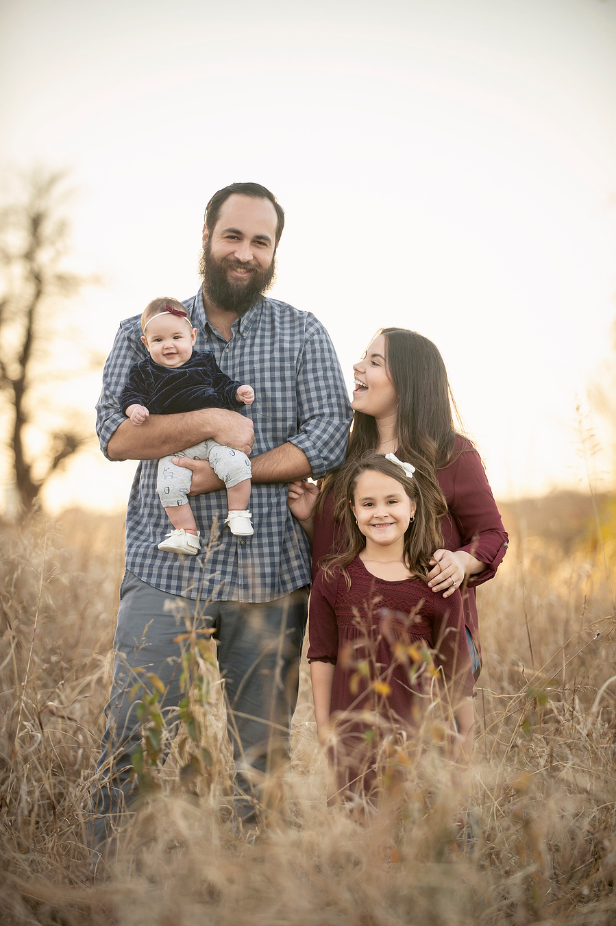 A family of four at golden hour in a field at White Rock Lake in Dallas