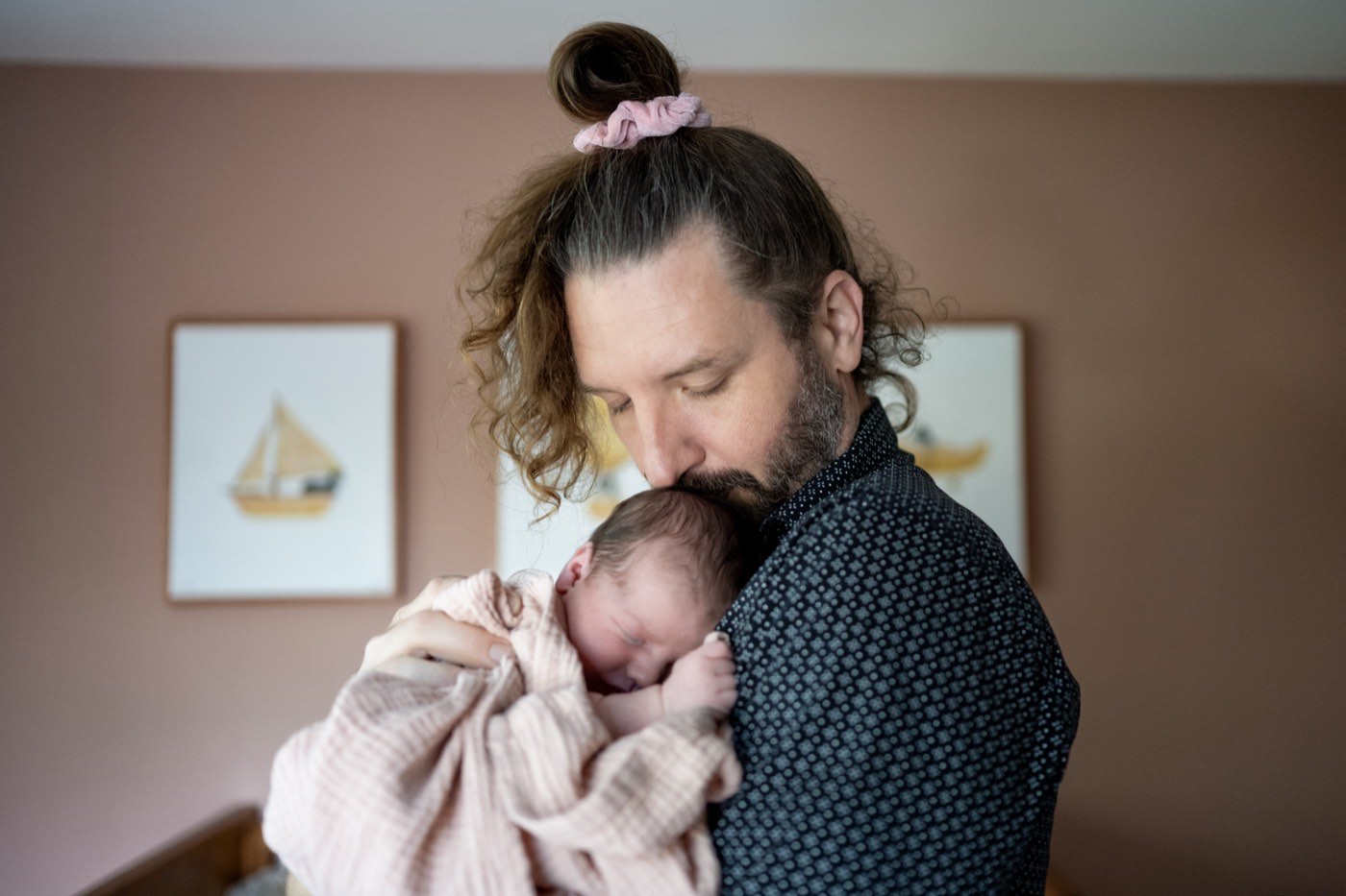 Erick Johnson holding his newborn daughter Isabella against his chest, kissing the top of her head