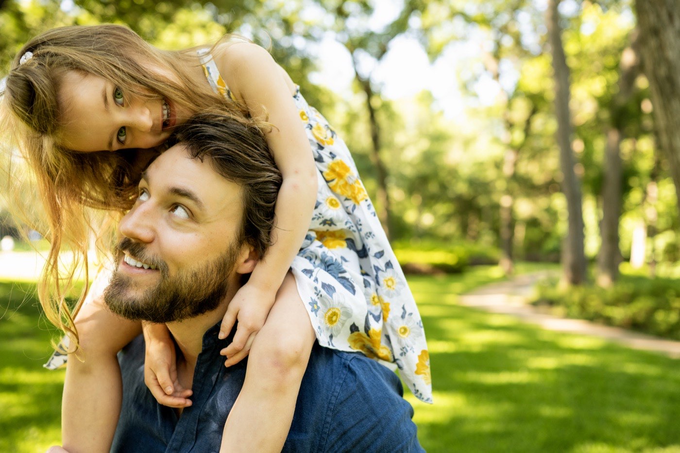 A father carrying his daughter on his shoulders at a Dallas family photography session