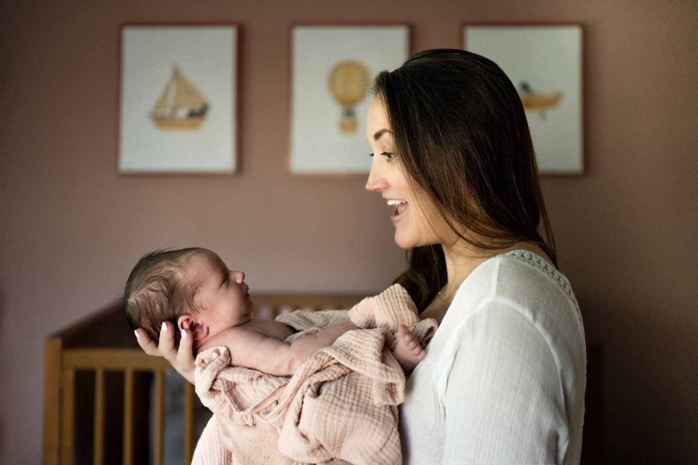 A Dallas mother smiling down at her newborn baby beside the crib